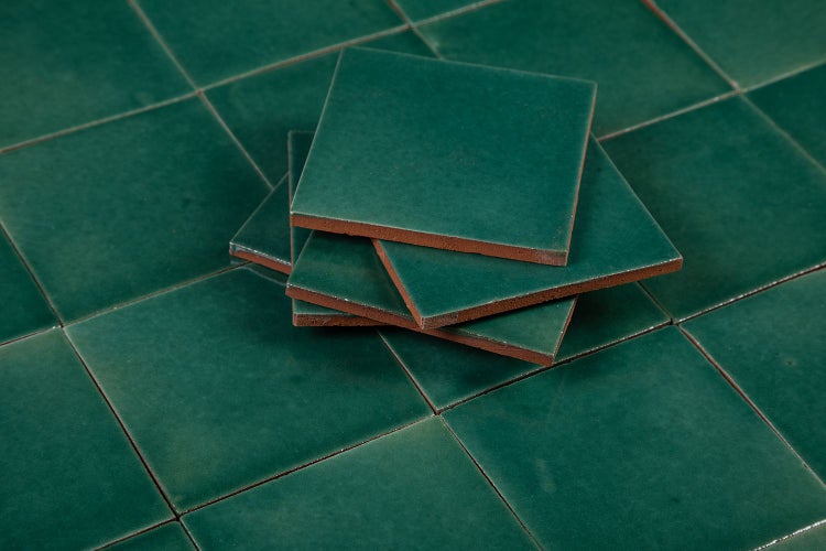 Quadratische, grüne Fliesen gestapelt auf weiteren Fliesen