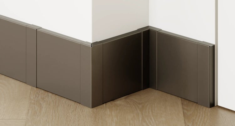 Innenaufnahme eines Raumes mit Sockelleisten aus Kunststoff an einer weißen Wand und einem Parkettboden in Fischgrätmuster