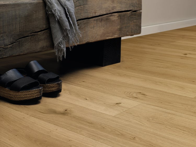 Holzoptik Laminatboden in Eichenoptik verlegt in einem Raum mit rustikalem Holzhocker und Schuhen.