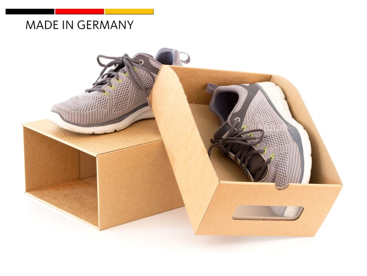 Ein Paar Sportschuhe aus Netzgewebe mit Schnürsenkeln in einer braunen Pappschachtel mit Sichtfenster und Siegel Hergestellt in Deutschland