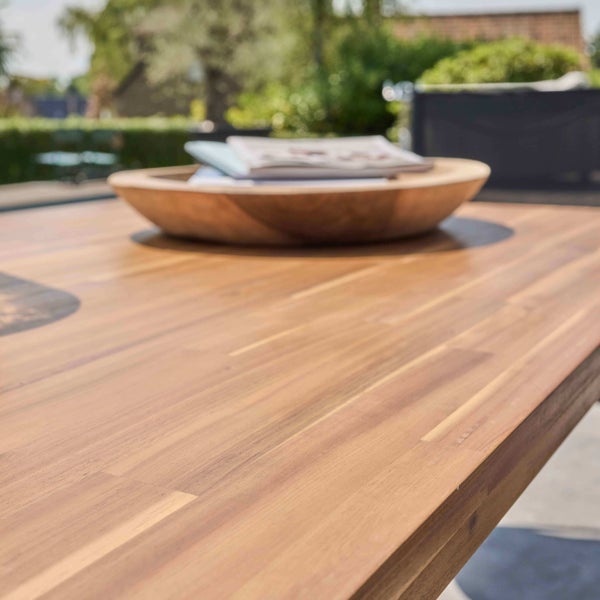 Nahaufnahme einer hölzernen Gartentischplatte mit sichtbarer Holzmaserung und einer darauf platzierten Holzschale.