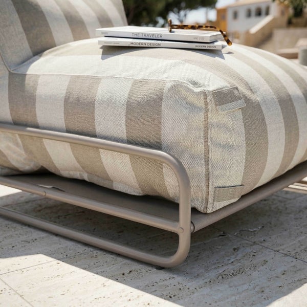 Moderner Garten-Loungesessel mit gestreiftem Polster aus Stoff und Metallgestell auf einer hellen, organisierten Terrasse.