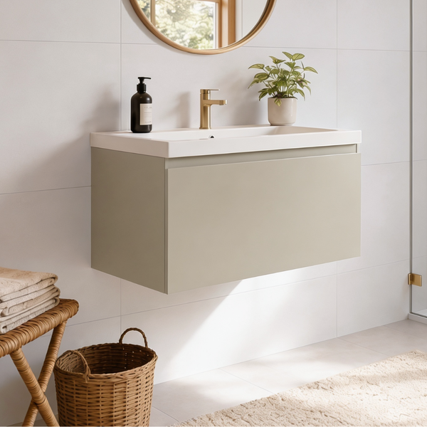 Moderner Wandwaschtisch mit Unterschrank in einem hellen Badezimmer mit goldenem Wasserhahn, rundem Spiegel und dekorativer Pflanze.