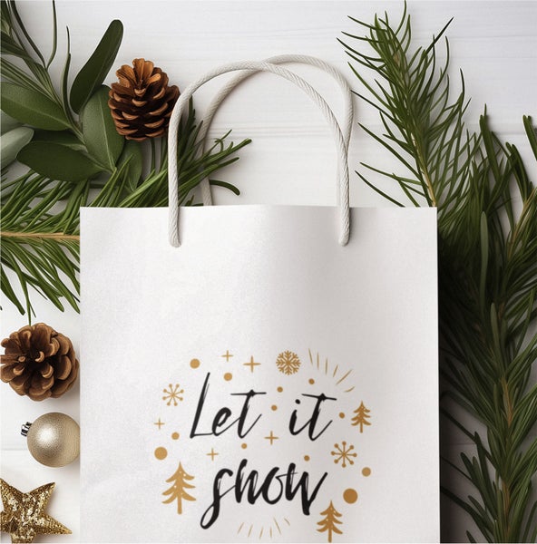 Geschenktüte mit 'Let it snow' Schriftzug, Tannenzweigen und Dekorationen