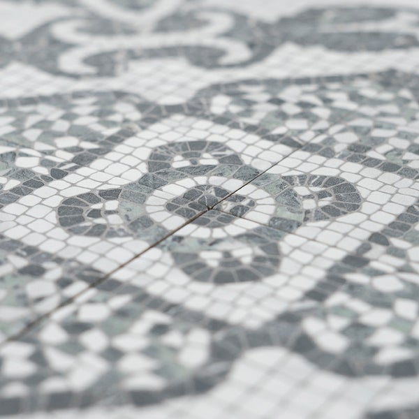 Fliese mit ornamentaler Mosaikoptik in quadratischem Format mit floralem Muster.