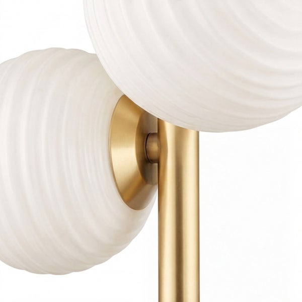 Detailansicht einer Leuchte mit zwei weißen Schirmen aus geriffeltem Glas und einem goldfarbenen Metallgestell.