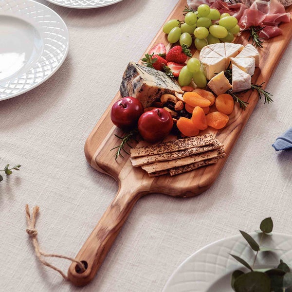 Holzbrett mit Käse, Wurst, Obst, Crackern und Nüssen auf einem Tisch