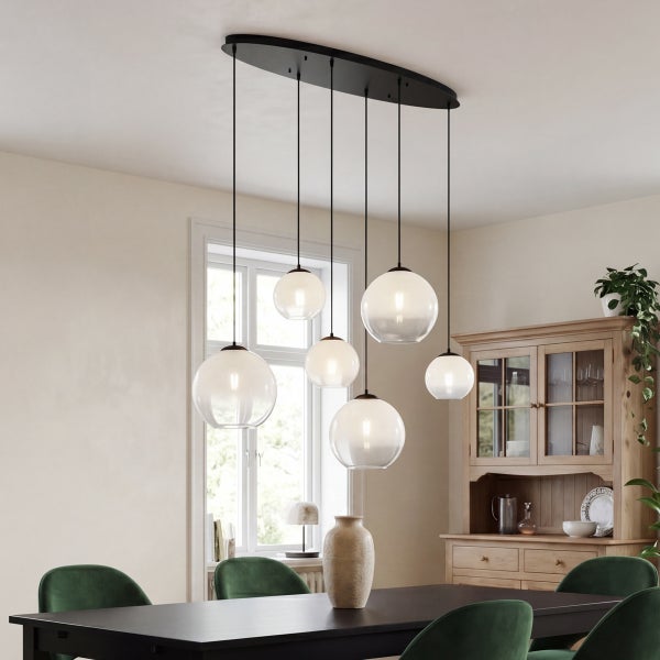 Moderne 7-flammige Pendelleuchte mit weißen Glaskugeln in verschiedenen Größen über einem dunklen Esstisch in einem hellen Esszimmer.