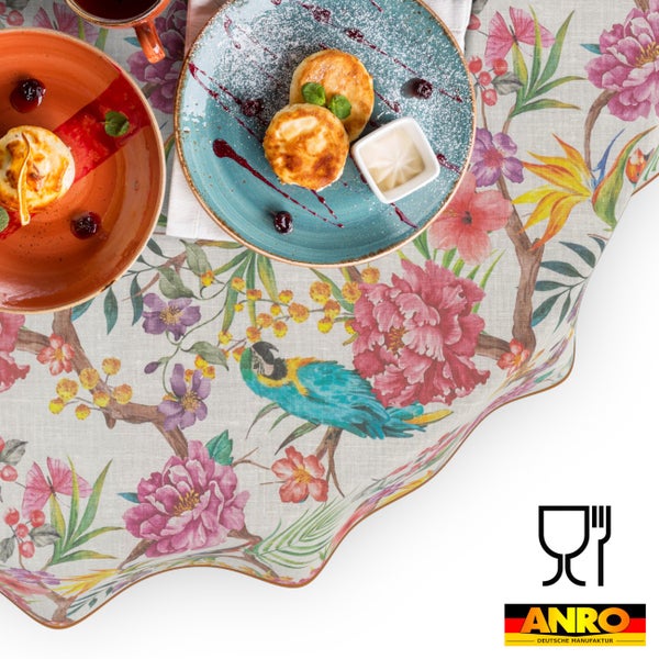 Tischdecke mit Blumenmuster und Papagei, Symbol für Lebensmittelechtheit und ANRO Logo.
