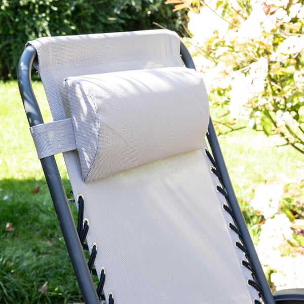 Garten-Relaxstuhl mit gepolsterter Kopfstütze und elastischer Schnürung des Textilgewebes am Metallrahmen in einem hellen Garten.