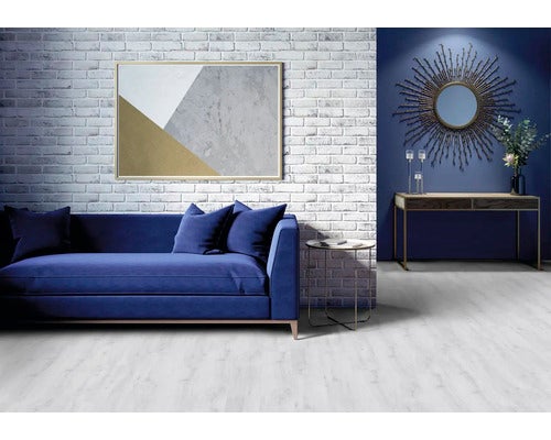 Wohnzimmer mit blauem Sofa, gemustertem Bild, Konsole, Spiegel und Beistelltisch vor einer Ziegelwand
