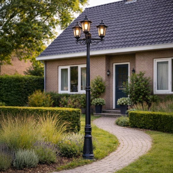 Dreiflammiger Kandelaber im klassischen Stil in einer Gartenanlage vor einem Einfamilienhaus.