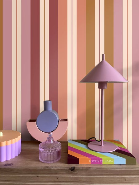 Modernes Zimmer mit vertikal gestreifter Tapete, Holzkommode mit Tischleuchte und dekorativen Vasen in einer ordentlichen Einrichtung.