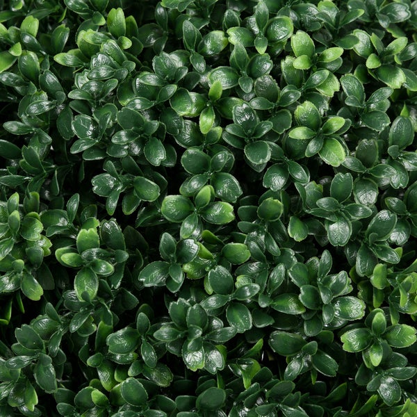 Nahaufnahme eines künstlichen Buchsbaums mit einem strukturierten Stamm und einem schwarzen Erdspieß.