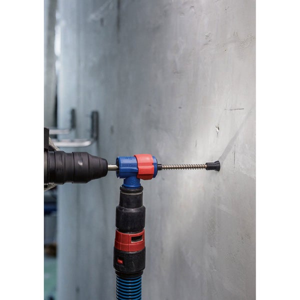 Eine Person bohrt mit einem Bohrhammer und Staubabsaugung in eine Wand.