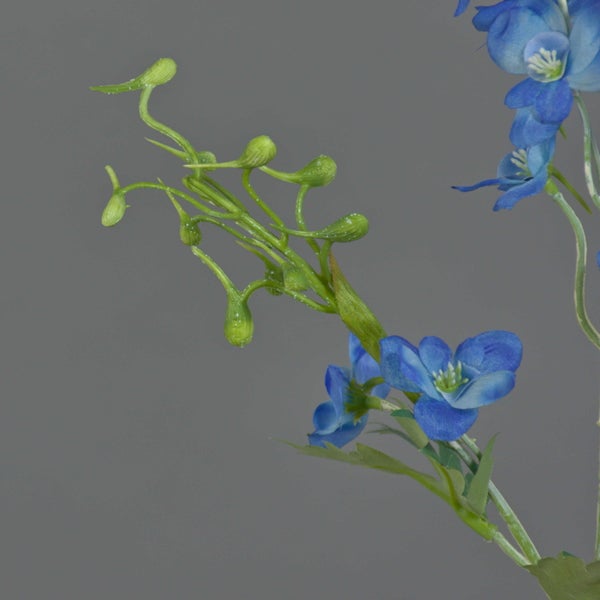 Künstlicher Rittersporn Zweig mit blauen Blüten und grünen Knospen.