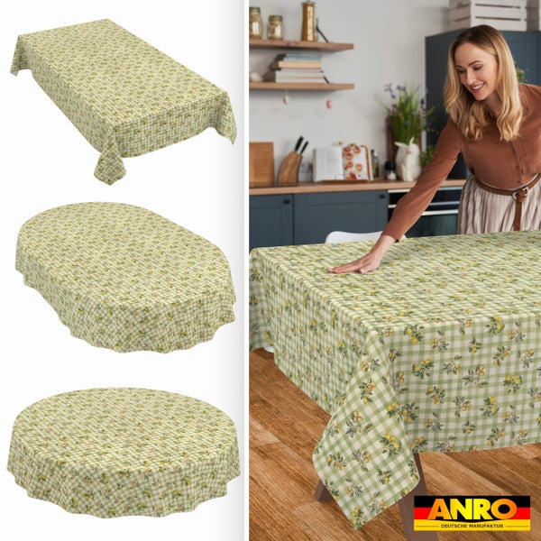 Tischdecke mit Karomuster und Zitronen-Design in rechteckig, oval und rund. Eine Frau legt die Decke auf einen Tisch in einer Küche. ANRO Logo.