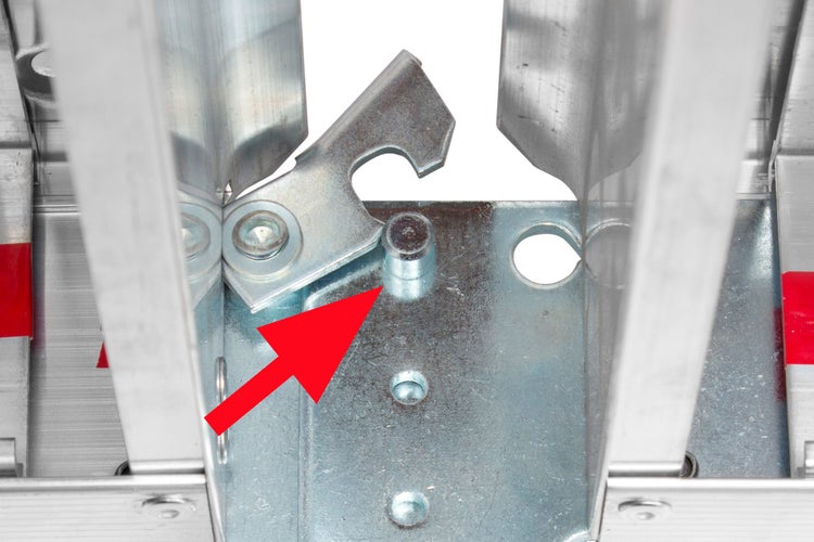 Nahaufnahme der Verriegelung eines Metallregals mit einem Pfeil, der auf den Sicherungsstift zeigt.