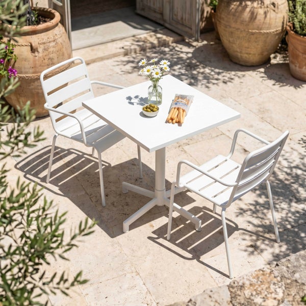 Modernes Gartenmöbelset aus weißem Metall mit quadratischem Tisch und zwei Stühlen auf einer sonnigen Terrasse mit Terrakottatöpfen.