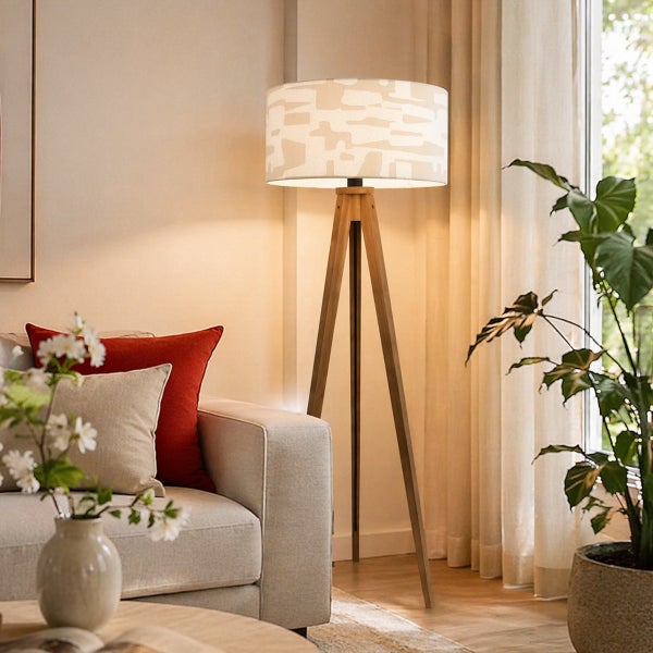Moderne Stativ Stehlampe mit Holzbeinen und gemustertem Lampenschirm in einem stilvoll eingerichteten Wohnzimmer.