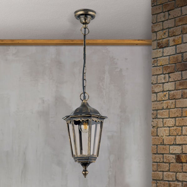 Klassische hängende Außenleuchte im Laternen-Stil aus Metall in Schwarz-Gold Antik-Optik mit Glaseinsätzen vor einer Backsteinwand.
