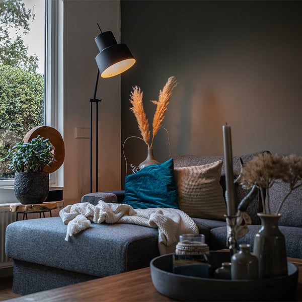 Wohnzimmer mit grauer Couch, Stehlampe und Dekorationen