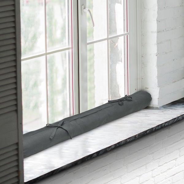 Zugluftstopper vor einem Fenster