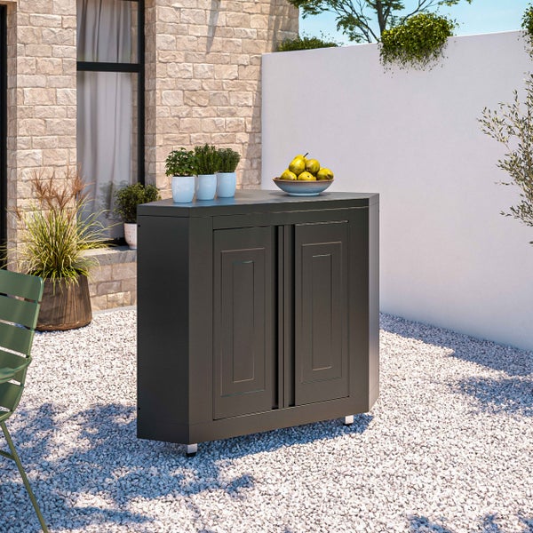 L-förmige Outdoor-Küche mit integriertem Gasgrill, Spülbecken und mehreren Unterschränken auf einer Holzterrasse vor einer grünen Kulisse.