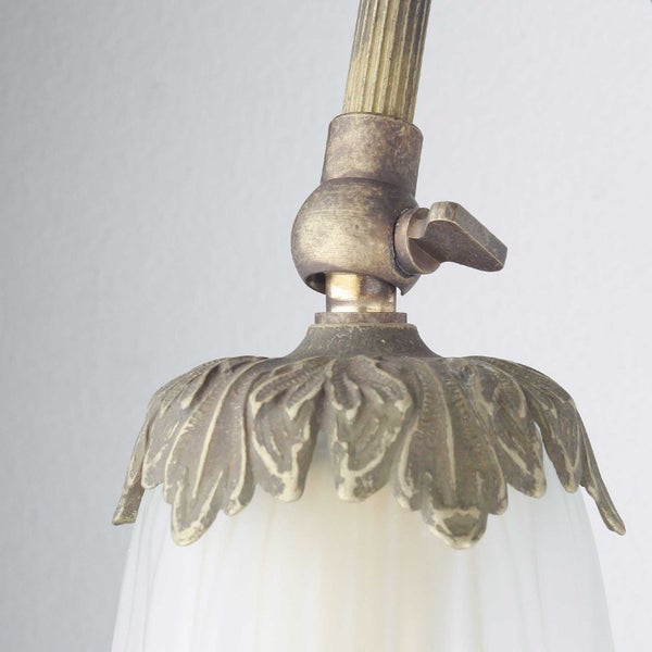 Detailansicht einer Lampe mit Metallelementen und einem Lampenschirm aus Glas