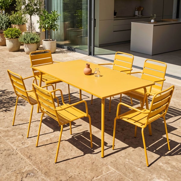 Moderne Garten-Essgruppe mit gelbem Metalltisch und sechs passenden Lattenstühlen auf einer hellen Steinterrasse.