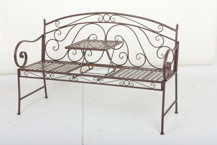 Braune Gartenbank aus Metall mit integriertem ausklappbarem Tisch und dekorativem Schnörkel-Design.