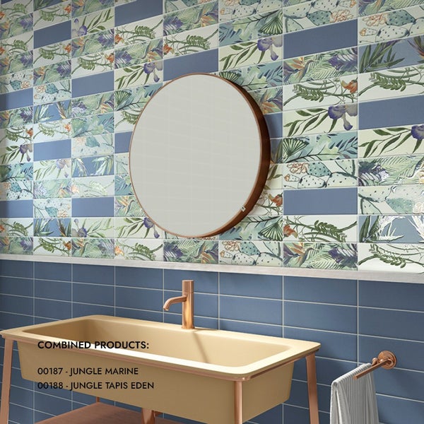 Modernes Badezimmer mit gemusterten Wandfliesen in Dschungeloptik und einfarbigen Fliesen, rundem Wandspiegel und Waschtisch mit Armatur.