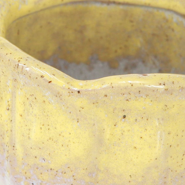 Nahaufnahme eines gelben Keramik-Pflanztopfs mit glasierter und gesprenkelter Oberfläche, Detailansicht von Rand und Textur.