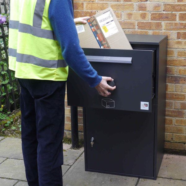 Eine Person legt ein Paket in einen Paketkasten.