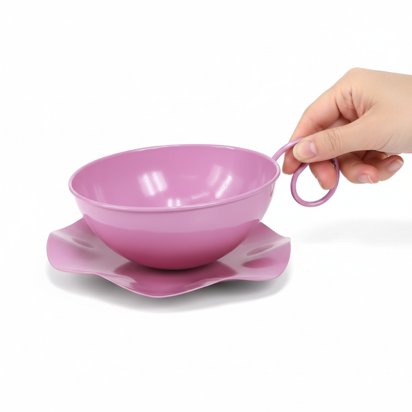 Lilafarbenes Pflanzgefäß aus Metall in Form einer Tasse mit Untersetzer, von einer Hand am Griff gehalten.