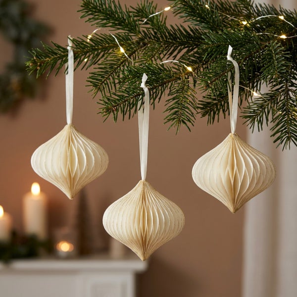 Drei dekorative Papierweihnachtskugeln in Wabenform mit Aufhängeschlaufen am Tannenbaum mit Lichterkette
