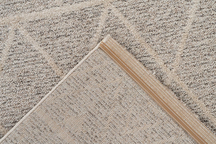 Detailaufnahme eines strukturierten Teppichs mit geometrischem Muster, die Oberfläche und die gewebte Rückseite mit verstärkter Kante zeigt.