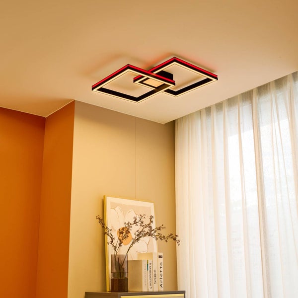 Moderne LED-Deckenleuchte mit zwei überlappenden quadratischen Rahmen in einem hellen Raum. Warmweißes Hauptlicht und rote Akzentbeleuchtung.