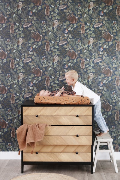 Dekorative Tapete mit Tiermuster, Wickelkommode mit Schubladen und Wickelauflage im Kinderzimmer