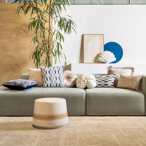 Wohnzimmer mit Sofa, Kissen, Beistelltisch, Teppich und Zimmerpflanze