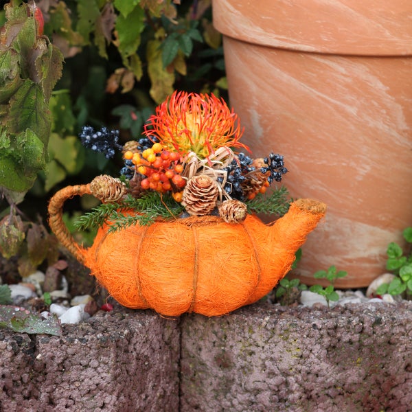 Dekorative Teekanne mit Herbstblumenarrangement als Gartendekoration