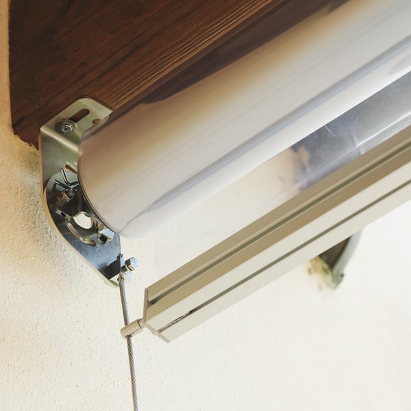 Detailaufnahme einer Senkrechtmarkise mit Seilführung und Metallhalterung an Wand und Holzbalken.