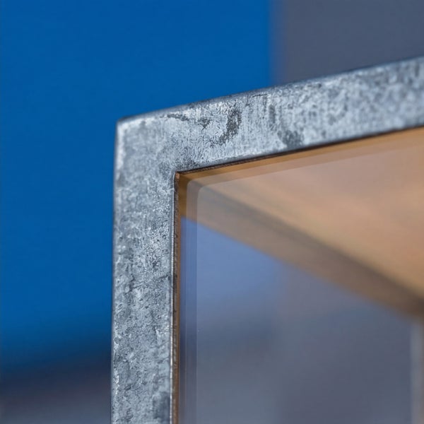 Nahaufnahme eines Leuchtenrahmens aus verzinktem Metall mit eingesetzter Glasscheibe.