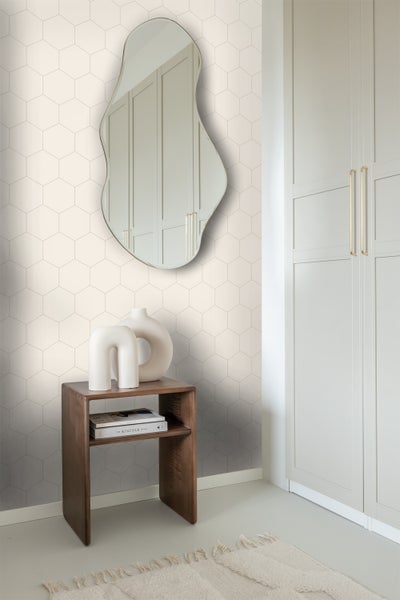 Helles Zimmer mit unregelmäßig geformtem Spiegel, kleinem Holztisch, weißen Dekorationsvasen, Büchern, gemusterter Tapete, Kleiderschrank und Teppich