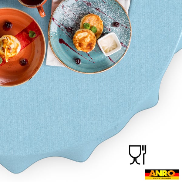 Hellblaue Tischdecke mit gewelltem Rand, strukturiertes Gewebe, gedeckter Frühstückstisch mit Tellern, Lebensmittelecht-Symbol, ANRO Logo.