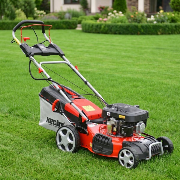 Roter Hecht Benzin-Rasenmäher mit Fangkorb auf einer grünen Rasenfläche in einem Garten.