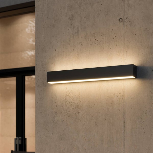 Moderne, schwarze, rechteckige LED-Außenwandleuchte an einer Betonwand mit warmweißem Lichtschein nach oben und unten.