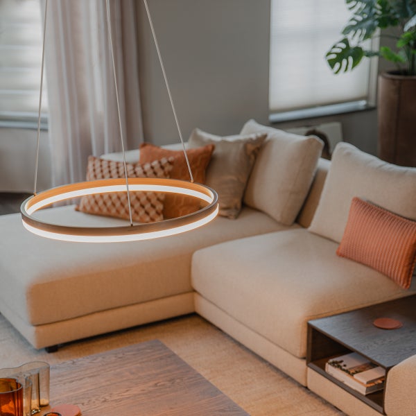 Einrichtung mit einem runden LED-Pendelleuchte über einem Sofa.