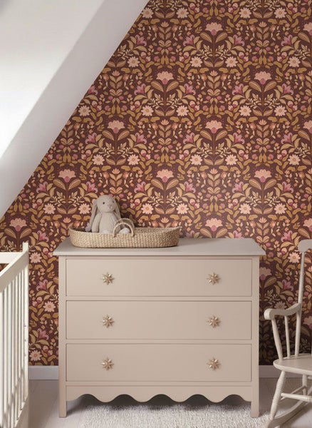 Kinderzimmer mit floral gemusterter Tapete, Kommode und Schaukelstuhl