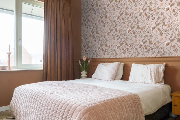 Schlafzimmer mit Doppelbett, Blumtapete und Vorhängen